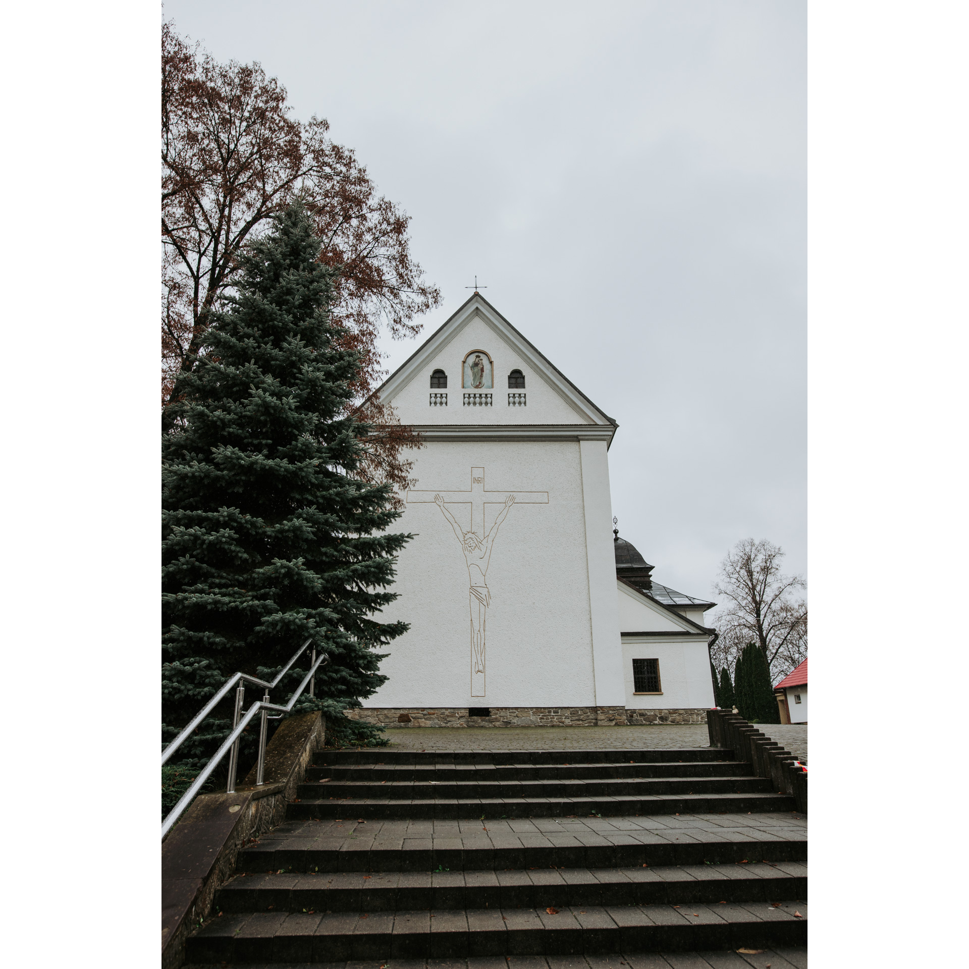 Stairs leading to a bright church building with Jesus painted on the cross on the wall and a triangular façade