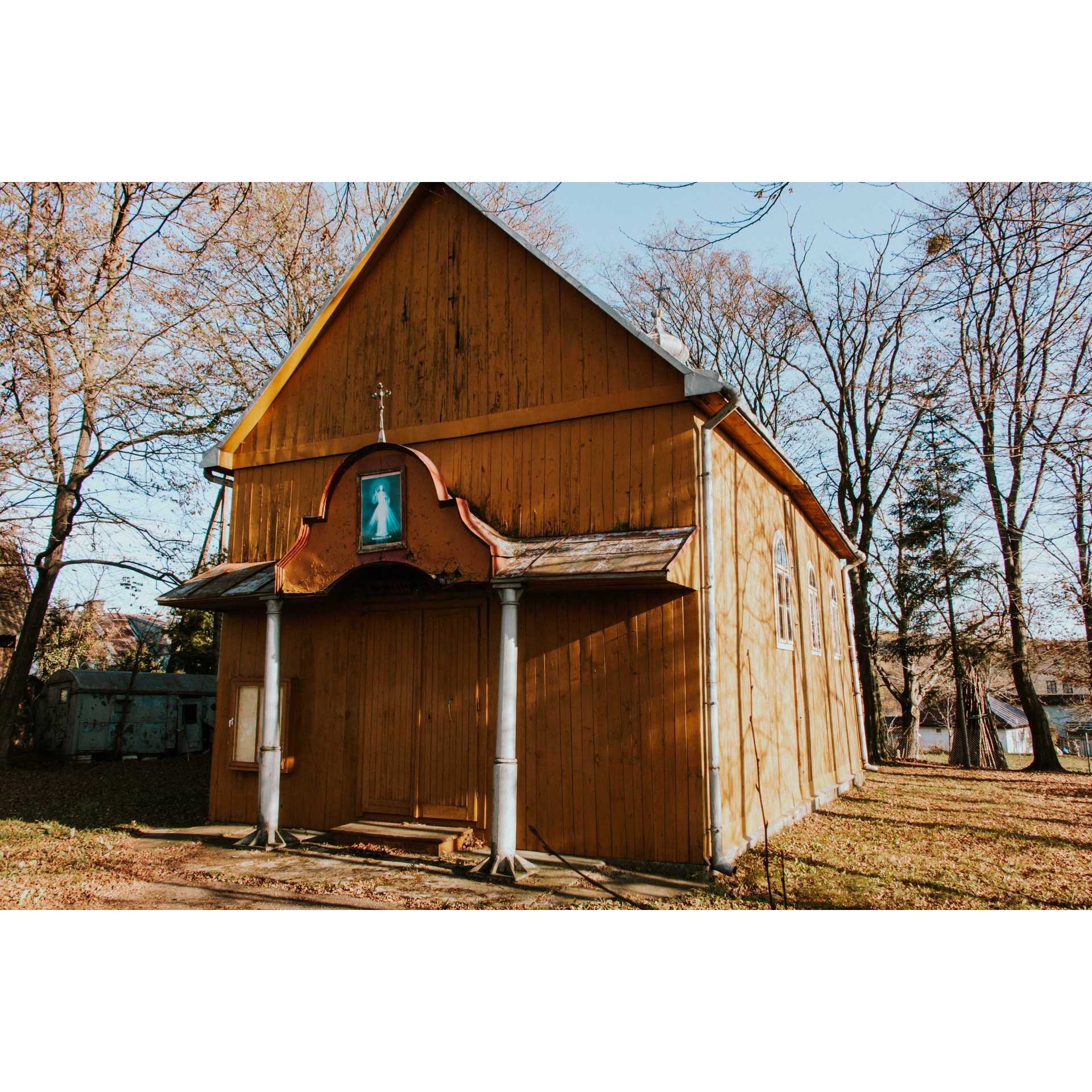 A wooden Orthodox church with a cross and a holy picture above the entrance