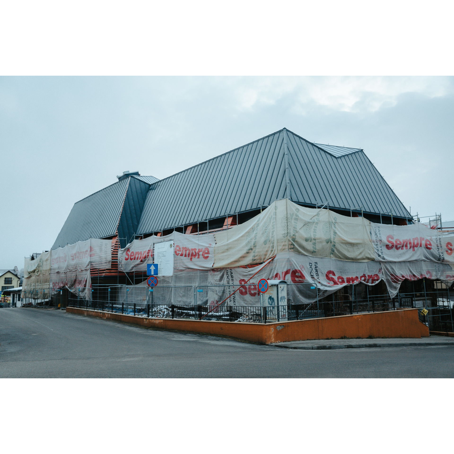 A building with a gray roof surrounded by protective white building material