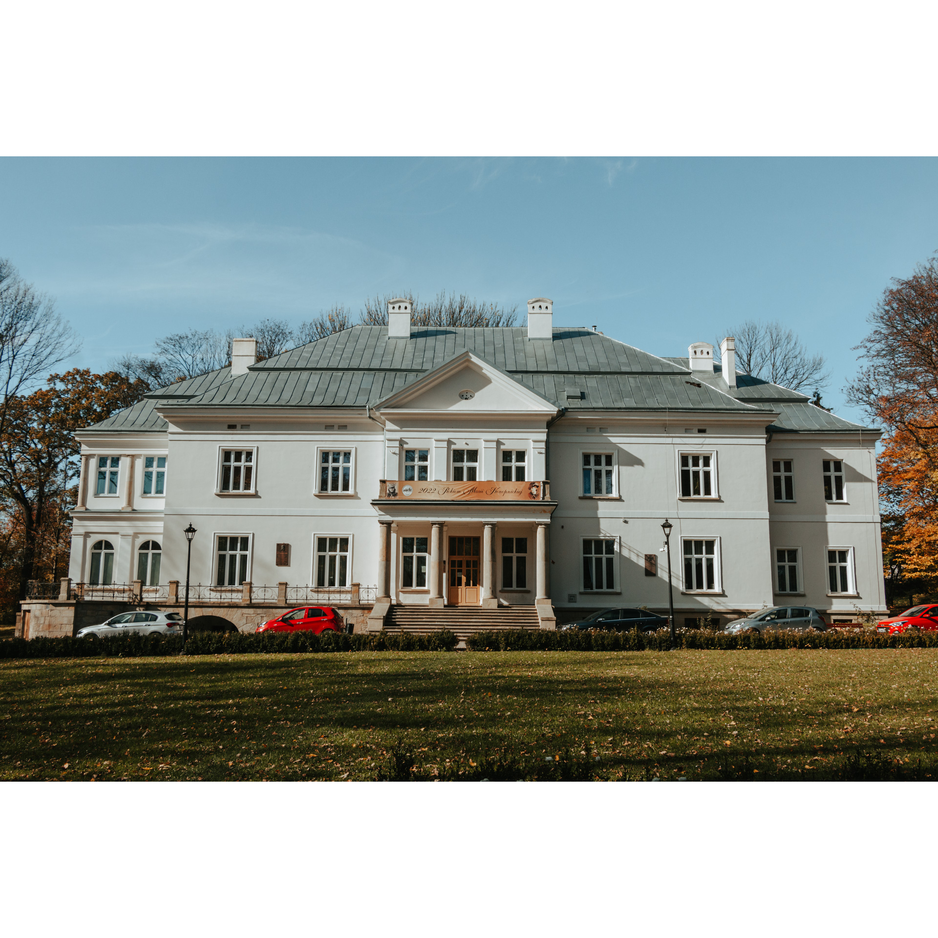 A large, white, brick mansion with four columns at the entrance