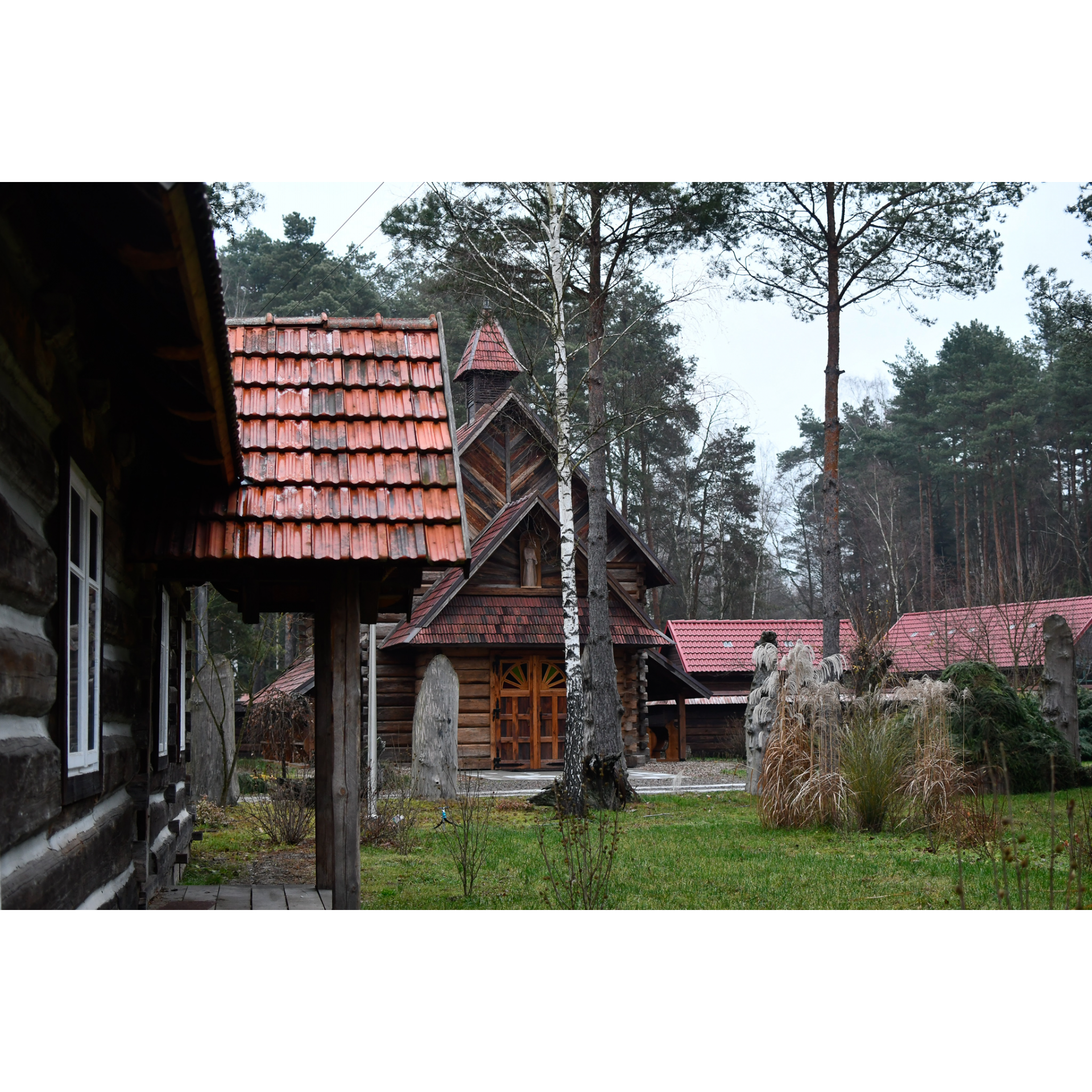 Widok na drewniane, małe domki na zielonej trawie wśród drzew