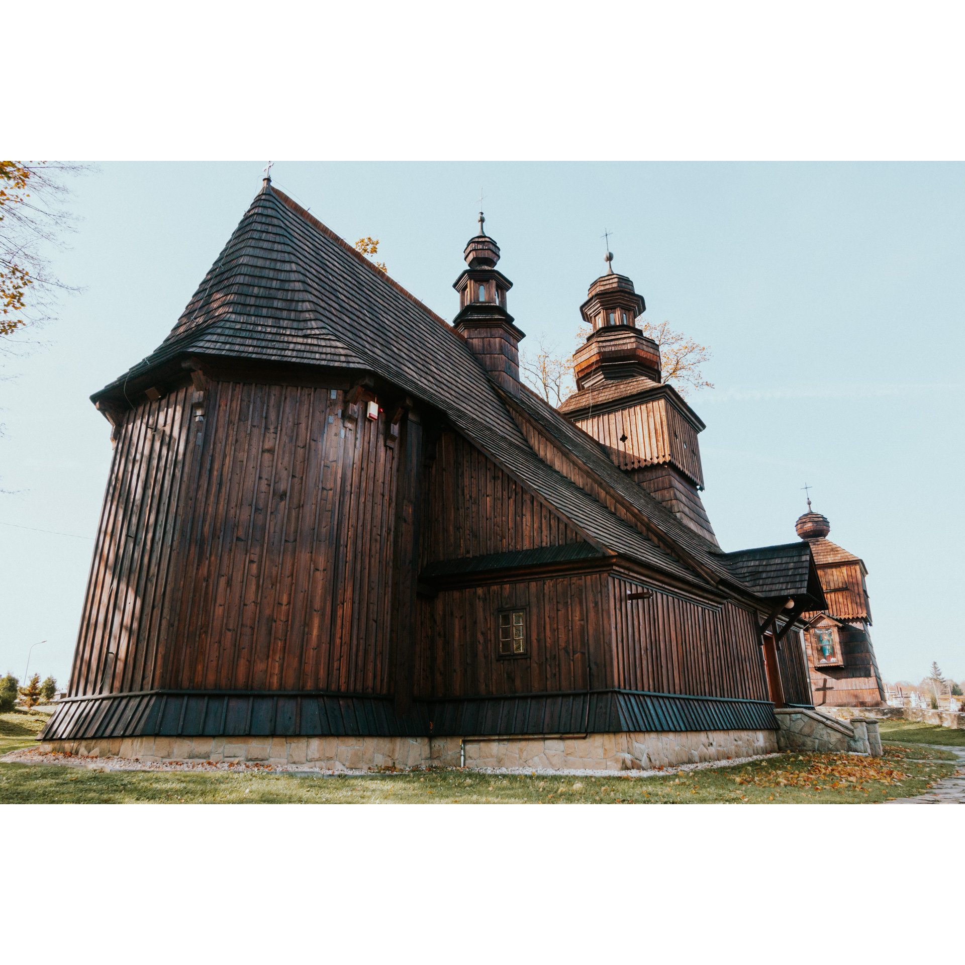 Bok drewnianego kościoła z podmurówką i kilkoma schodami na tle jasnego nieba