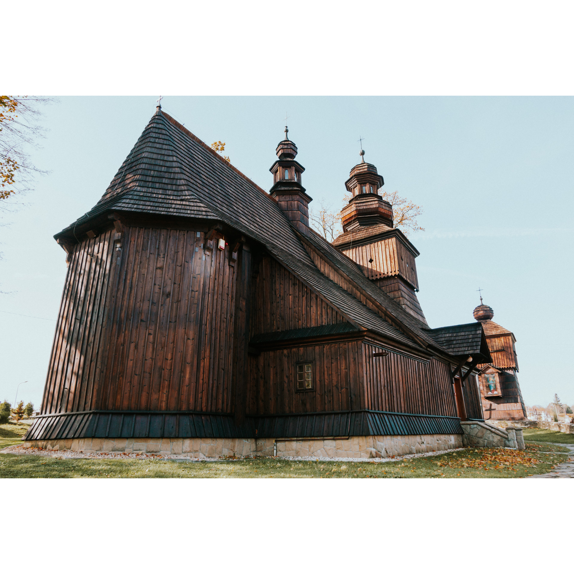 The side of a wooden church with a foundation and several stairs against a bright blue sky