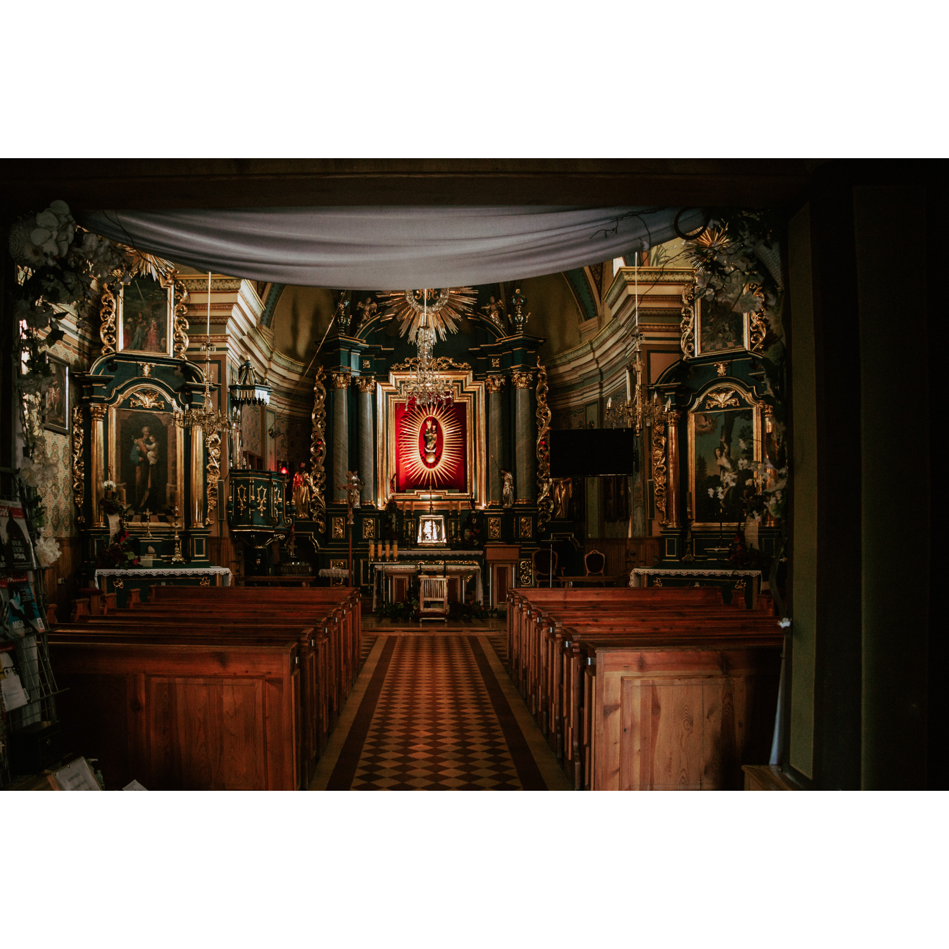 Bogato zdobiony ołtarz sanktuarium - w centralnej części niewielka figura Matki Boskiej z Dzieciątkiem otoczona złotym zdobieniem i ramą, po bokach obrazy świętych zdobione polichromią, przed ołtarzem drewniane ławki dla wiernych