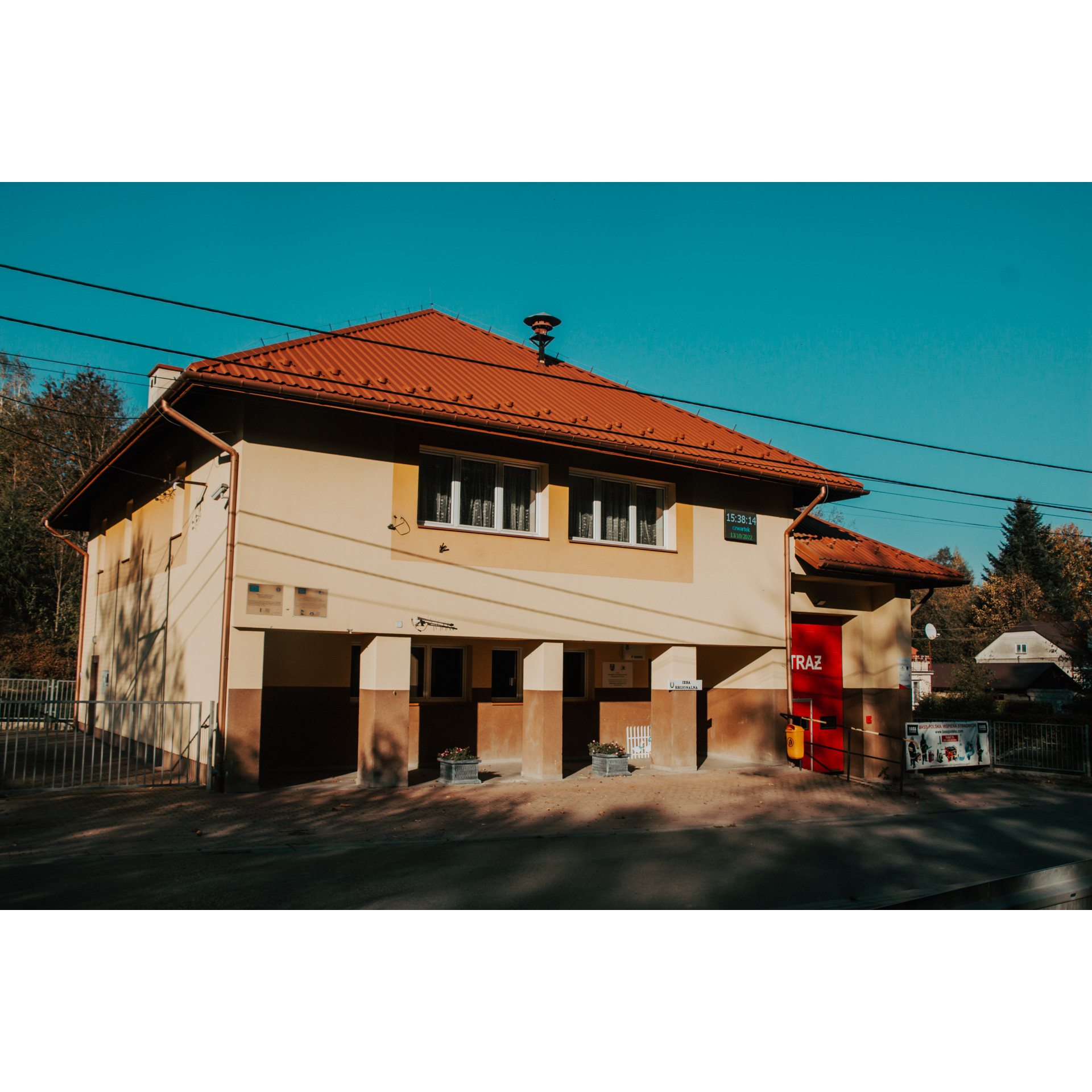 A small square brick building with simple square porticoes, a red guard door on the right