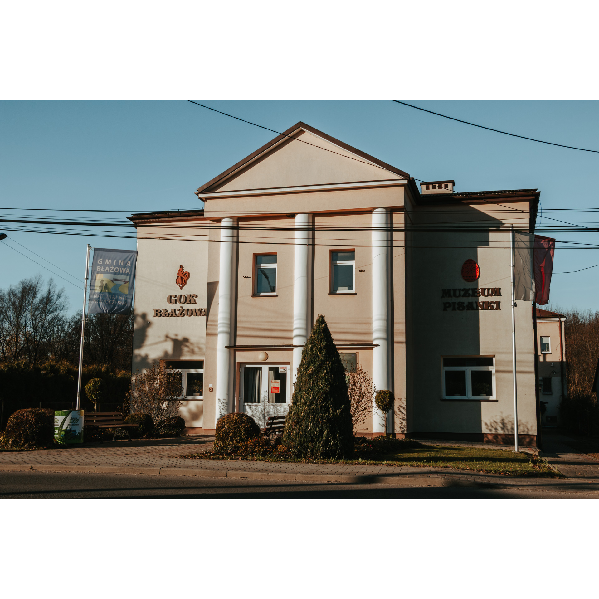 A tall, bright building with three columns and a flagpole