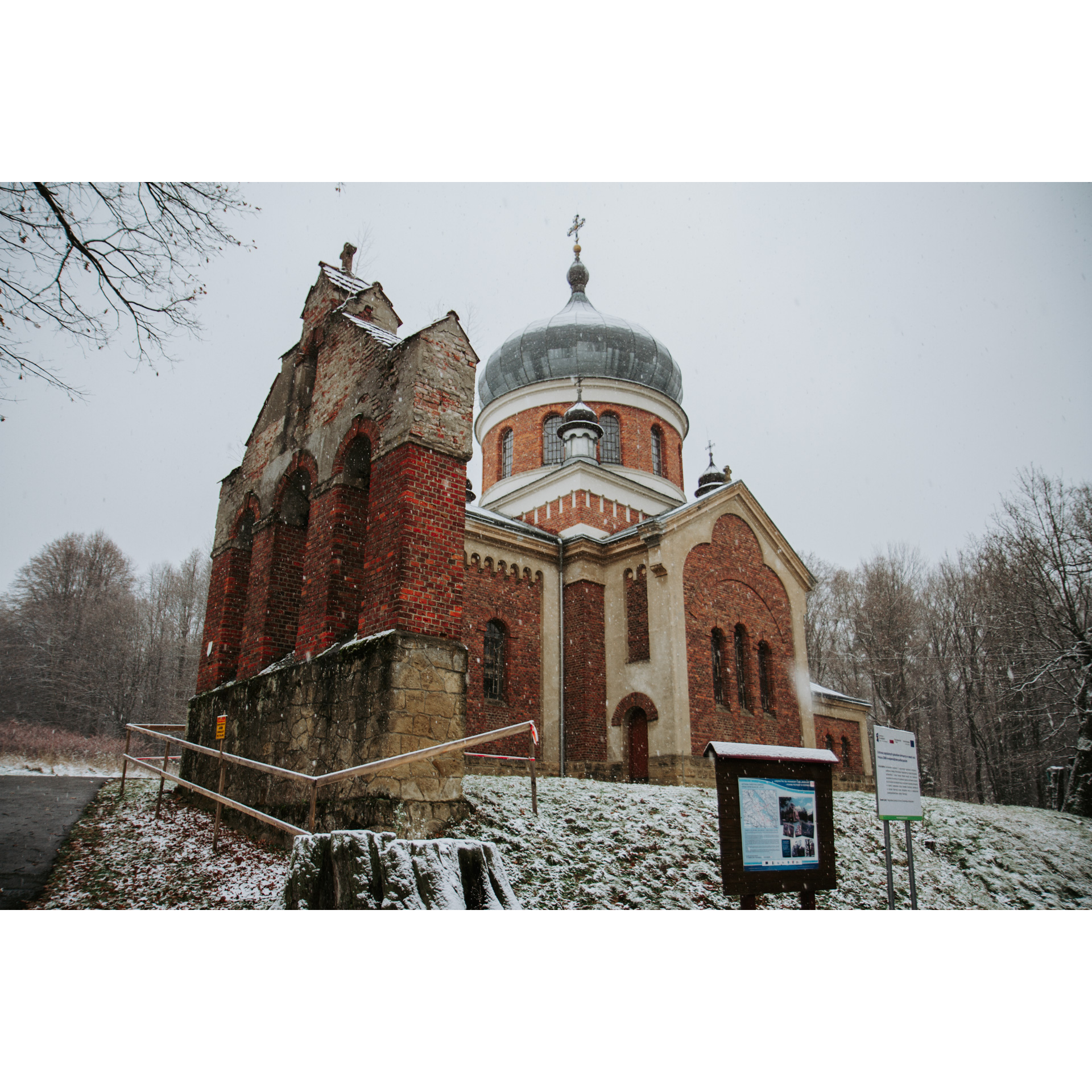 A red brick church with an old bell tower on a snow-covered hill