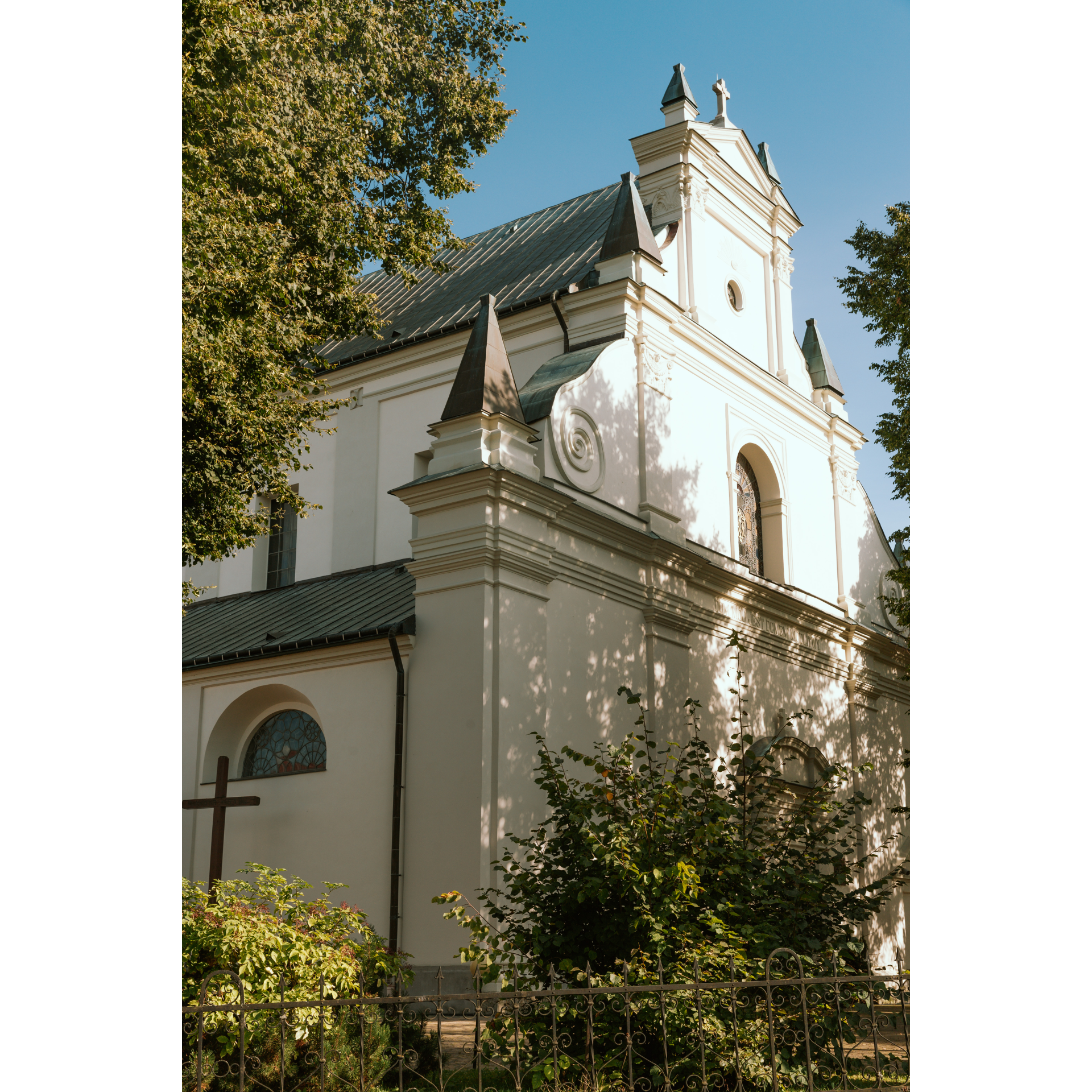 Kościół o jasnym kolorze fasady, półokrągłe okna i strzeliste daszki i wieżyczki oraz ozdobne rzeźbienia na froncie