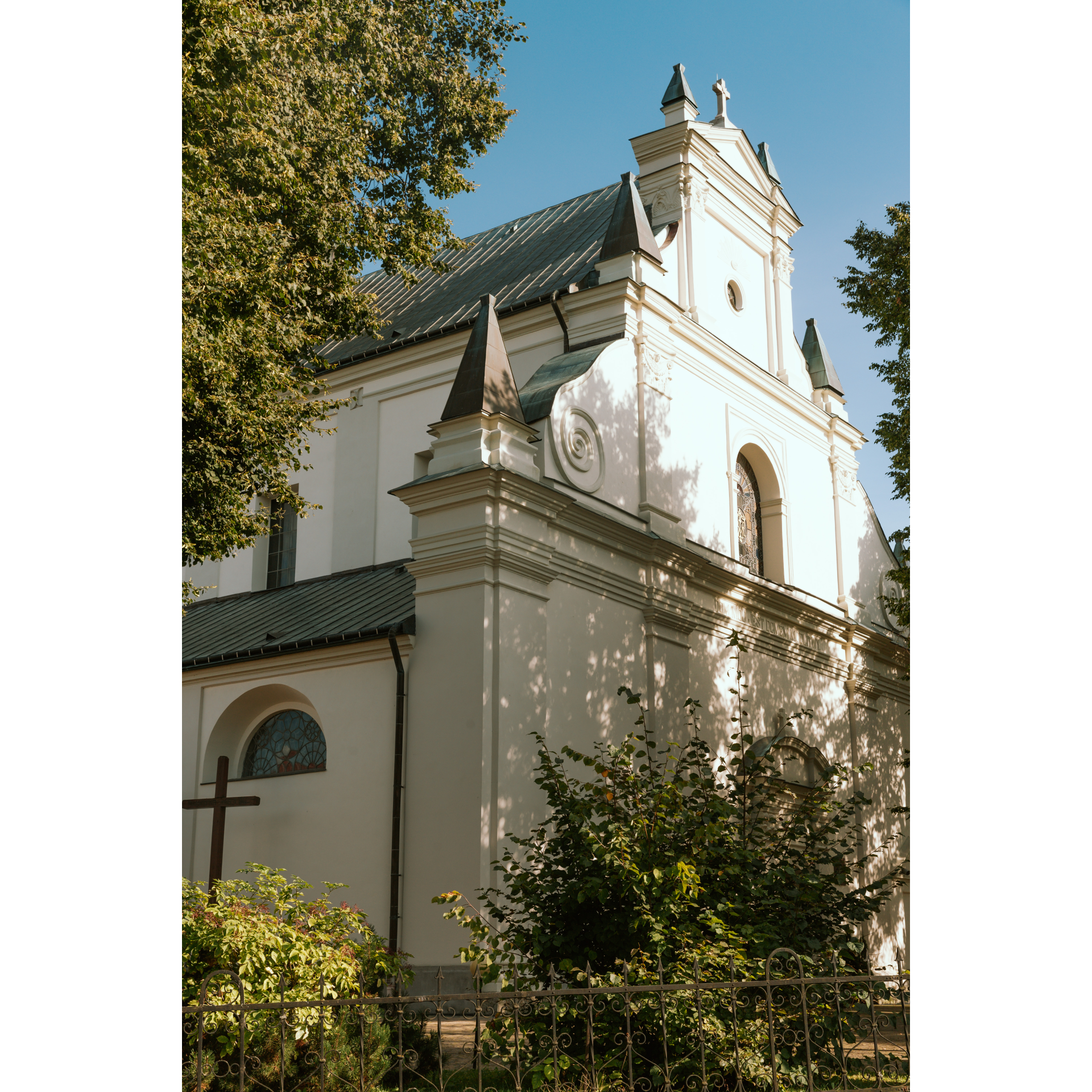 A church with a light-colored facade, semi-circular windows and soaring roofs and turrets, as well as decorative carvings on the front.