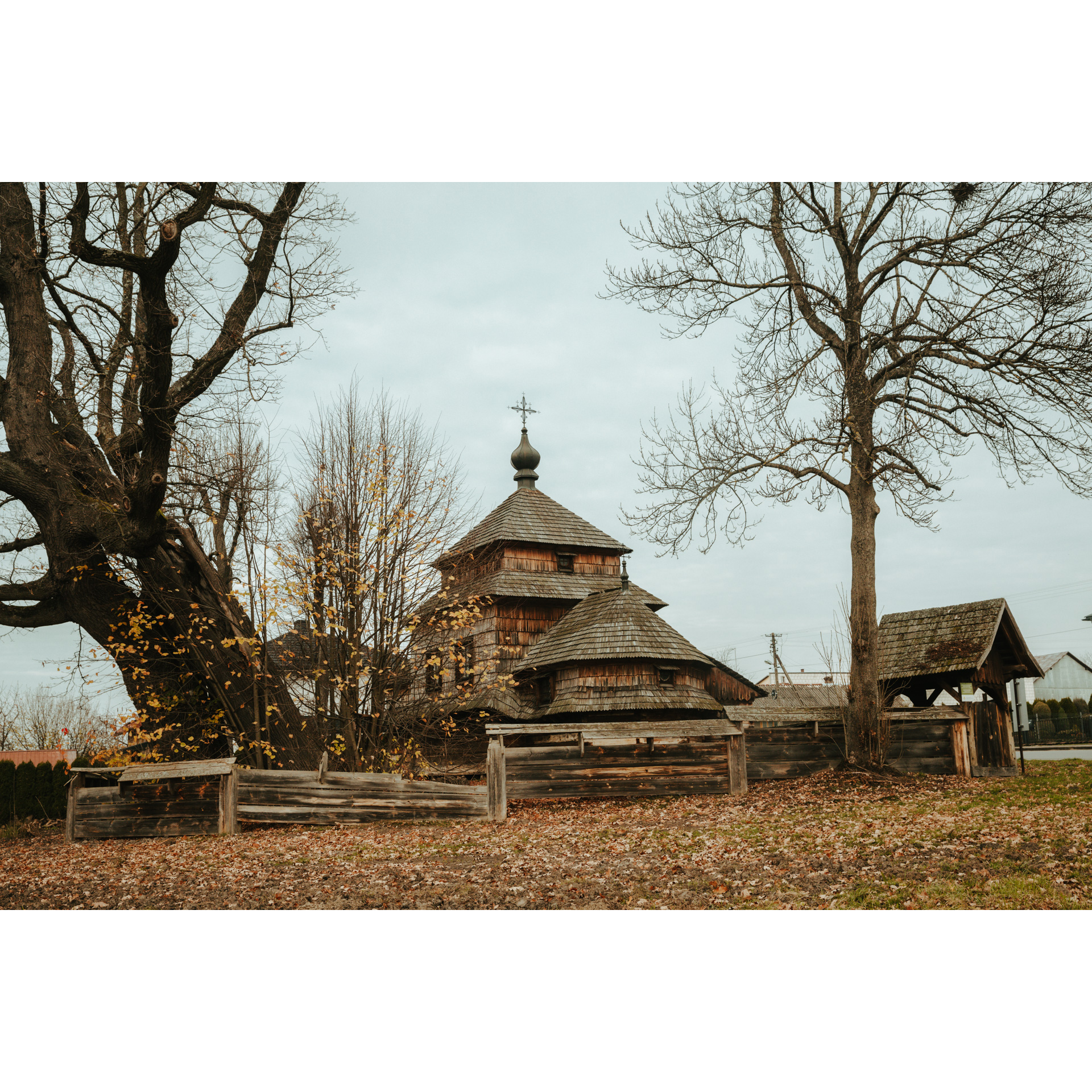 A wooden church surrounded by a wooden fence among trees