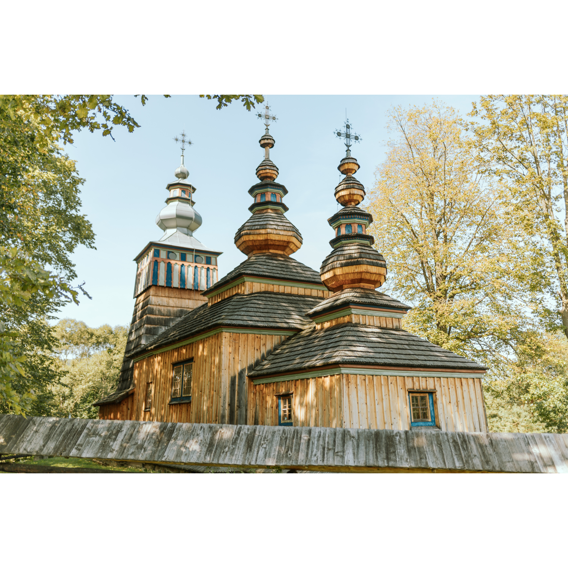 A three-part wooden church, with each part topped with a dome, hipped roofs and a tower with a pillar structure