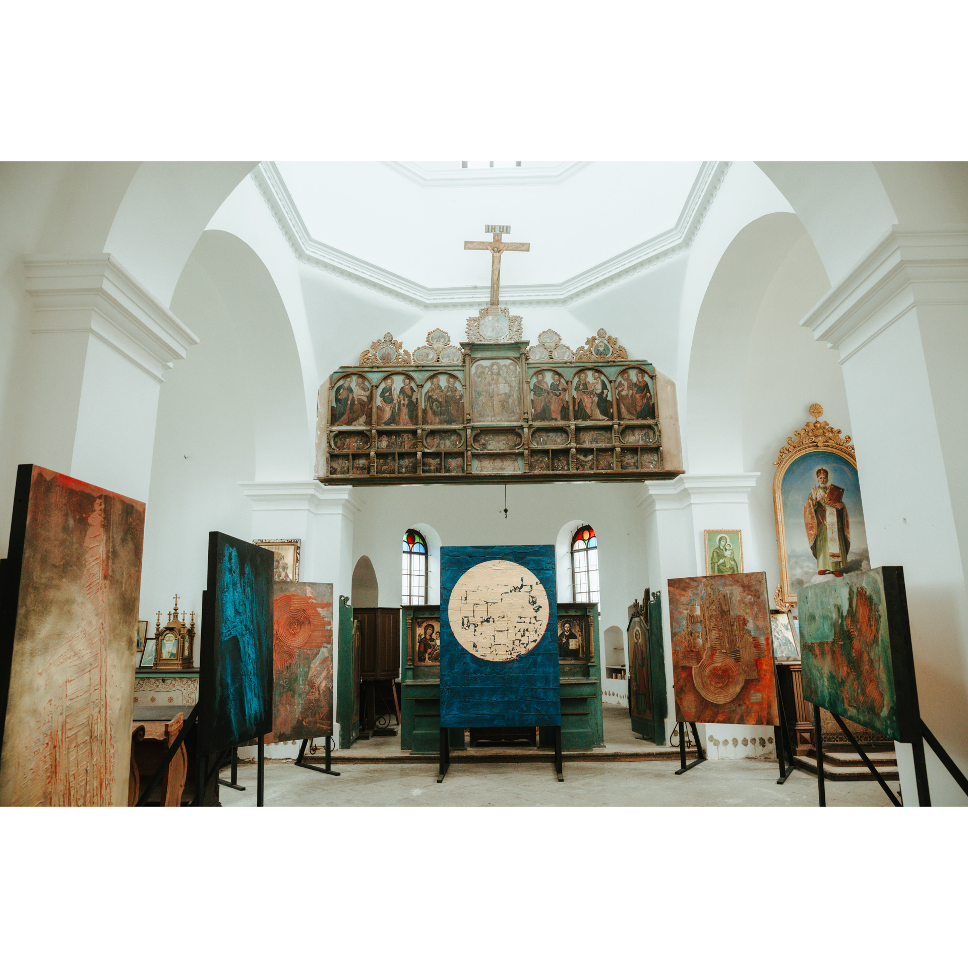 The white interior of the church with the iconostasis at the top and colorful paintings standing on the ground