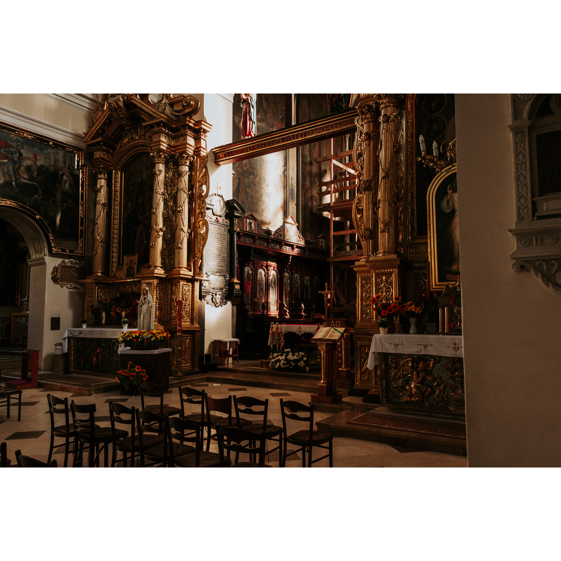 Ołtarz we wnętrzu kościoła ze złotymi i czerwonymi wykończeniami oraz świętymi obrazami