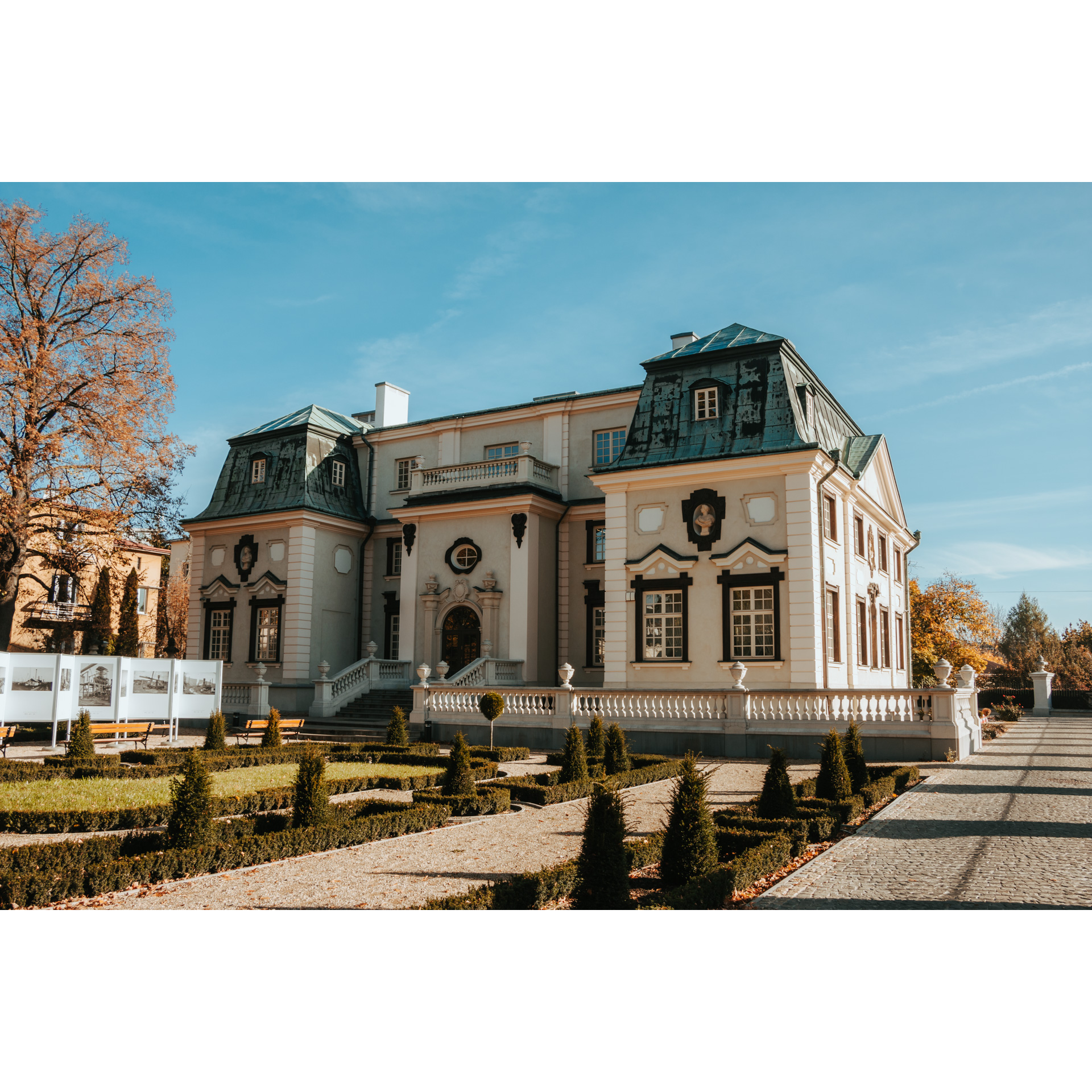 Beżowy pałac o zielonym dachu z szerokimi schodami wykończonymi dekoracyjną, kamienną balustradą