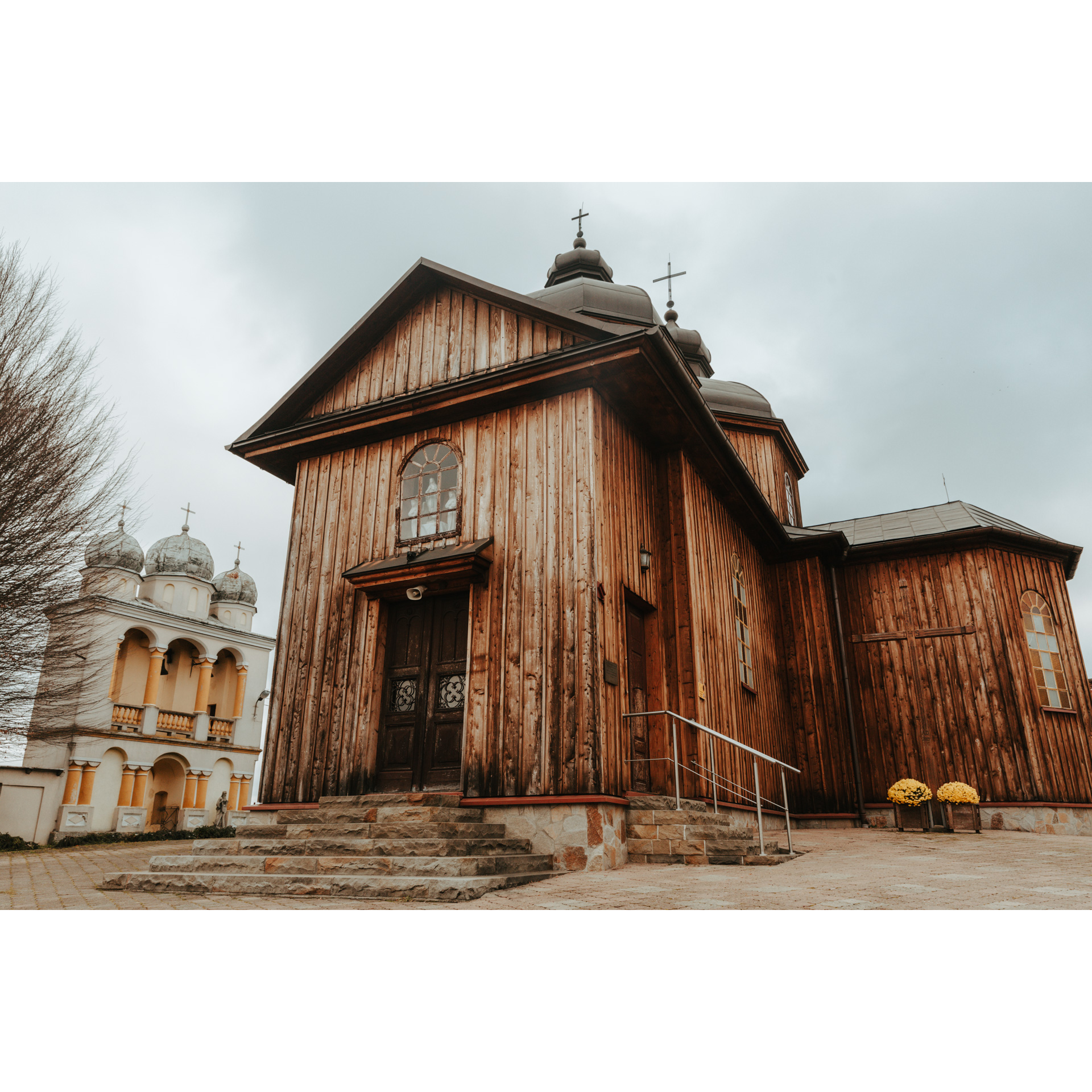 A wooden church against the background of a concrete, bright belfry