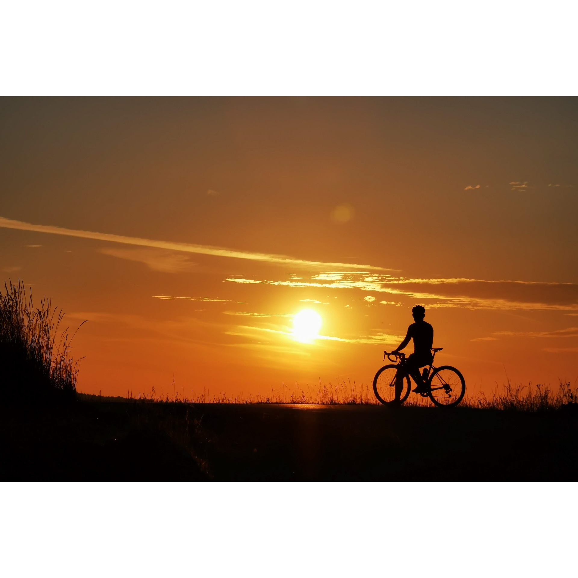 Rowerzysta siedzący na rowerze na tle zachodzącego słońca
