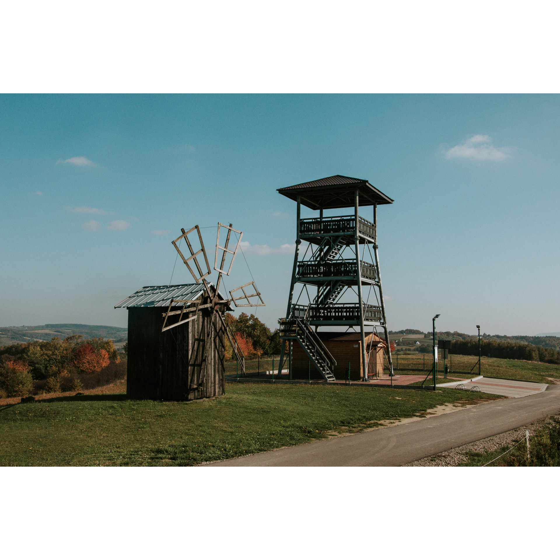 Drewniany wiatrak i drewniana wieża widokowa ze schodami na wzgórzu