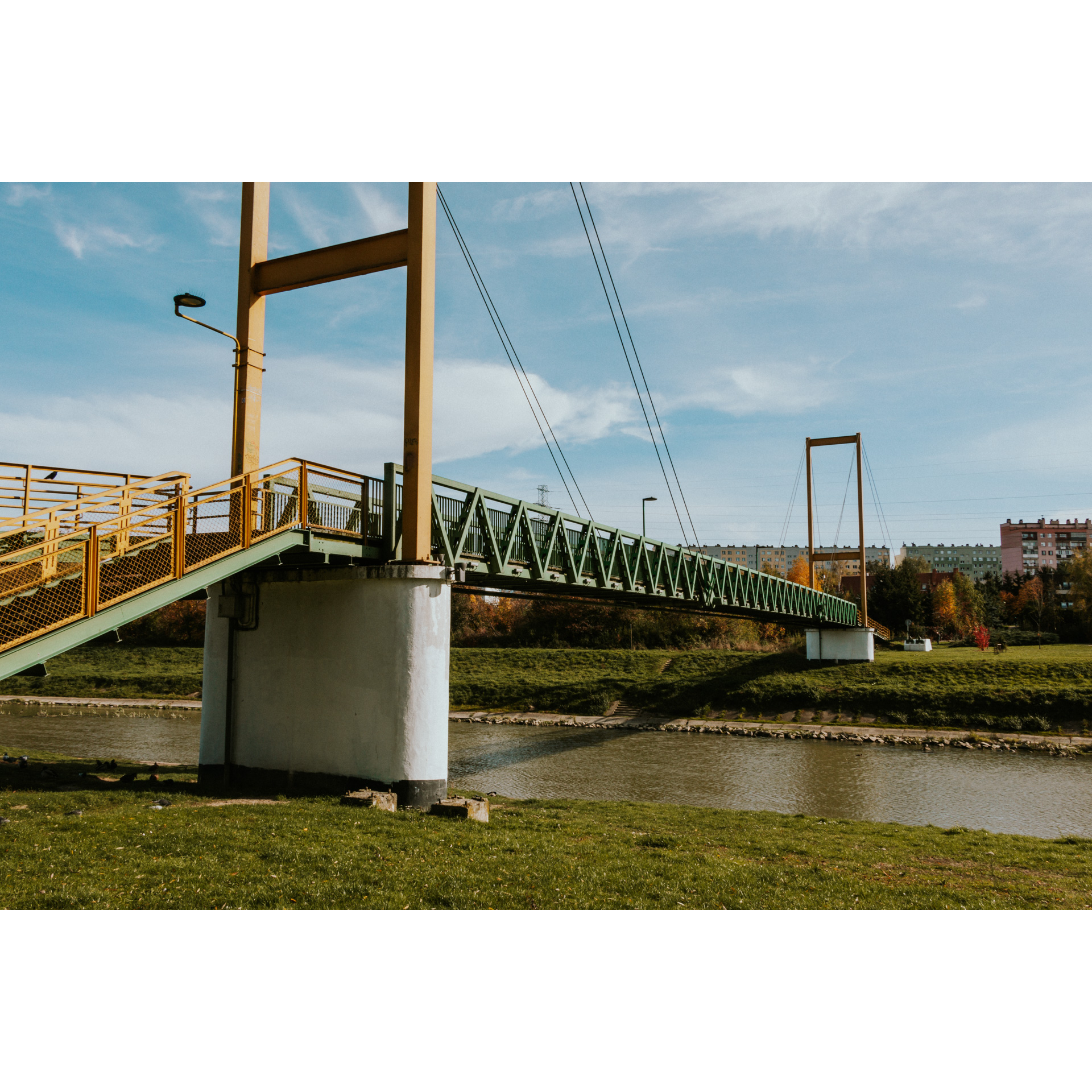 Kładka dla pieszych nad rzeką z zieloną balustradą