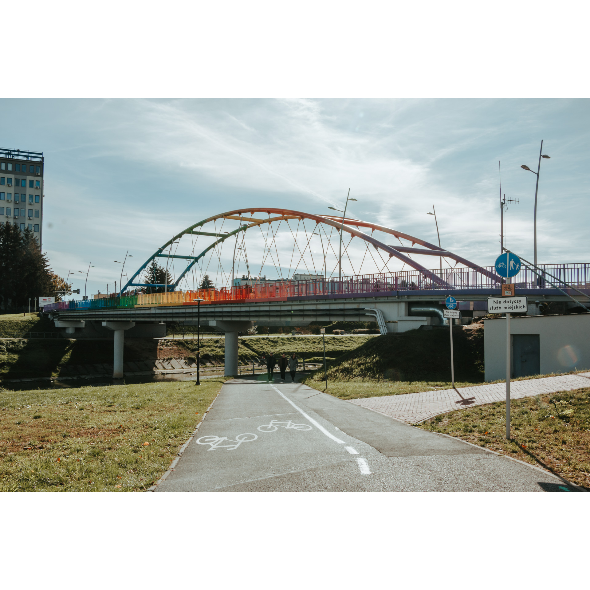 Path for pedestrians and cyclists in the background a rainbow bridge with a semi-circular structure