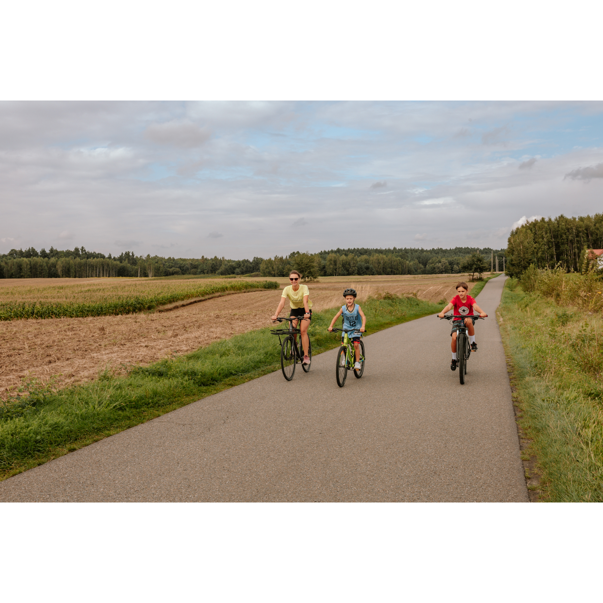 A cyclist with children among the fields