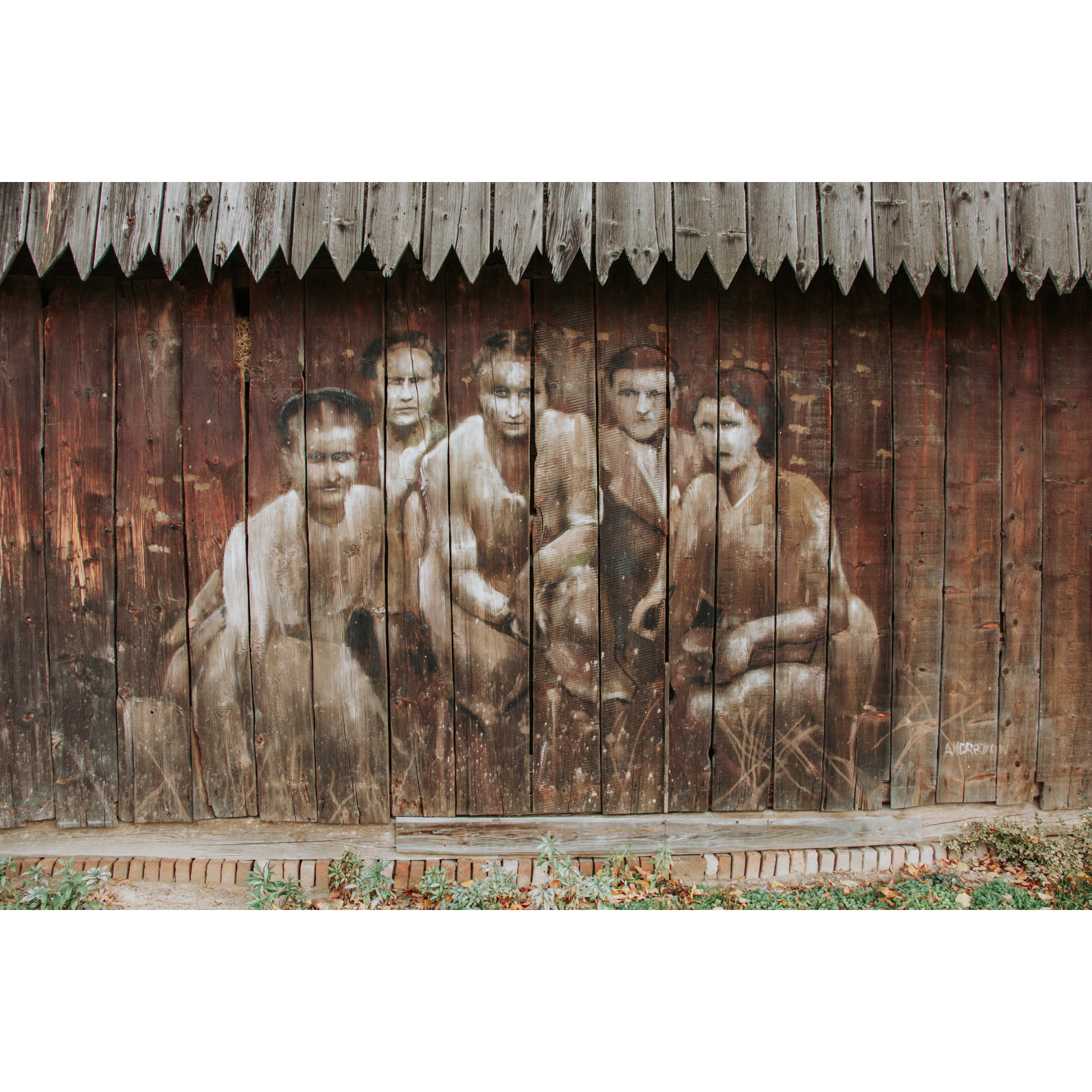 Rysunek w brązowo-beżowych barwach na drewnianej ścianie przedstawiający 3 kobiety z przodu i dwóch mężczyzn z tyłu