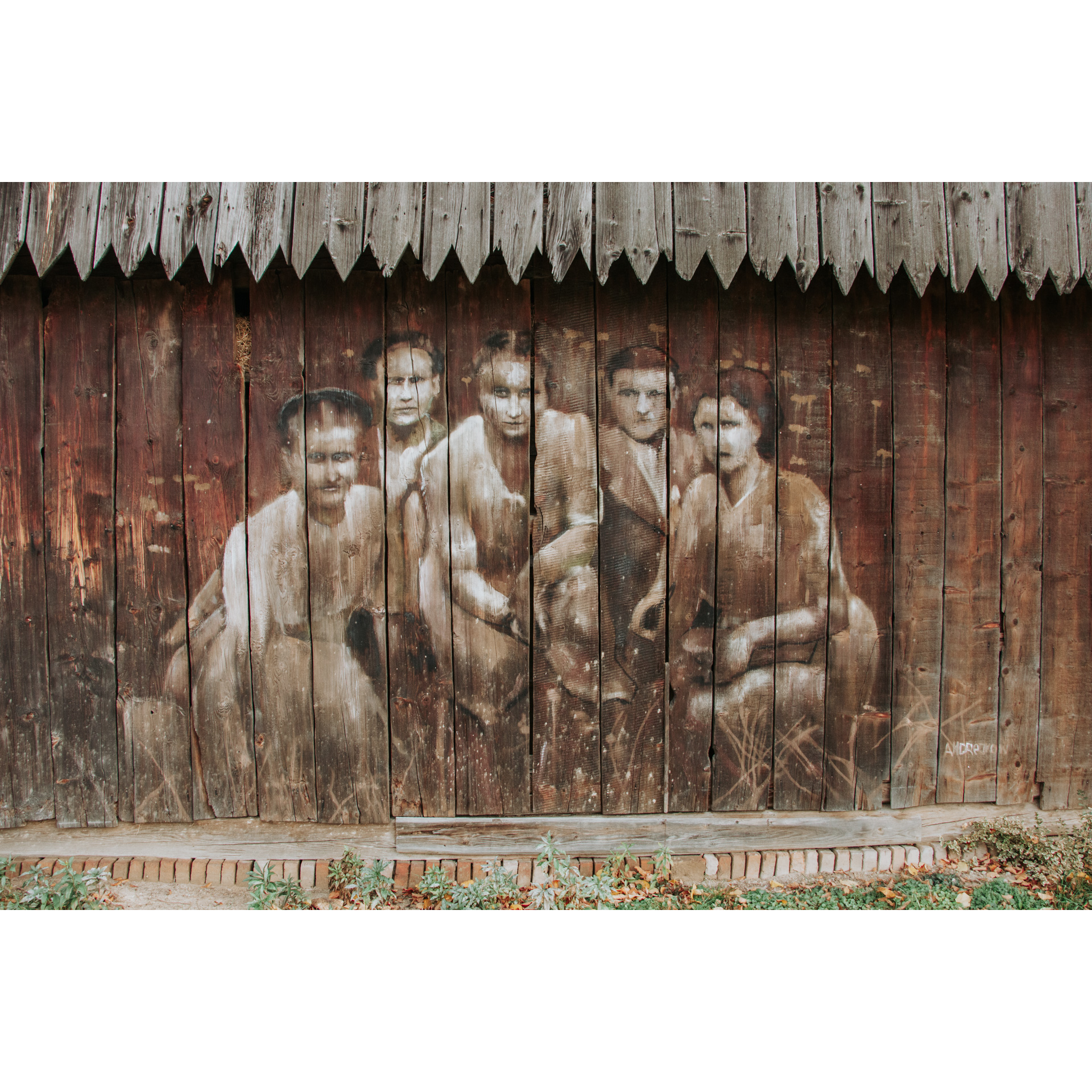 A drawing in brown and beige colors on a wooden wall showing 3 women in front and two men in the back