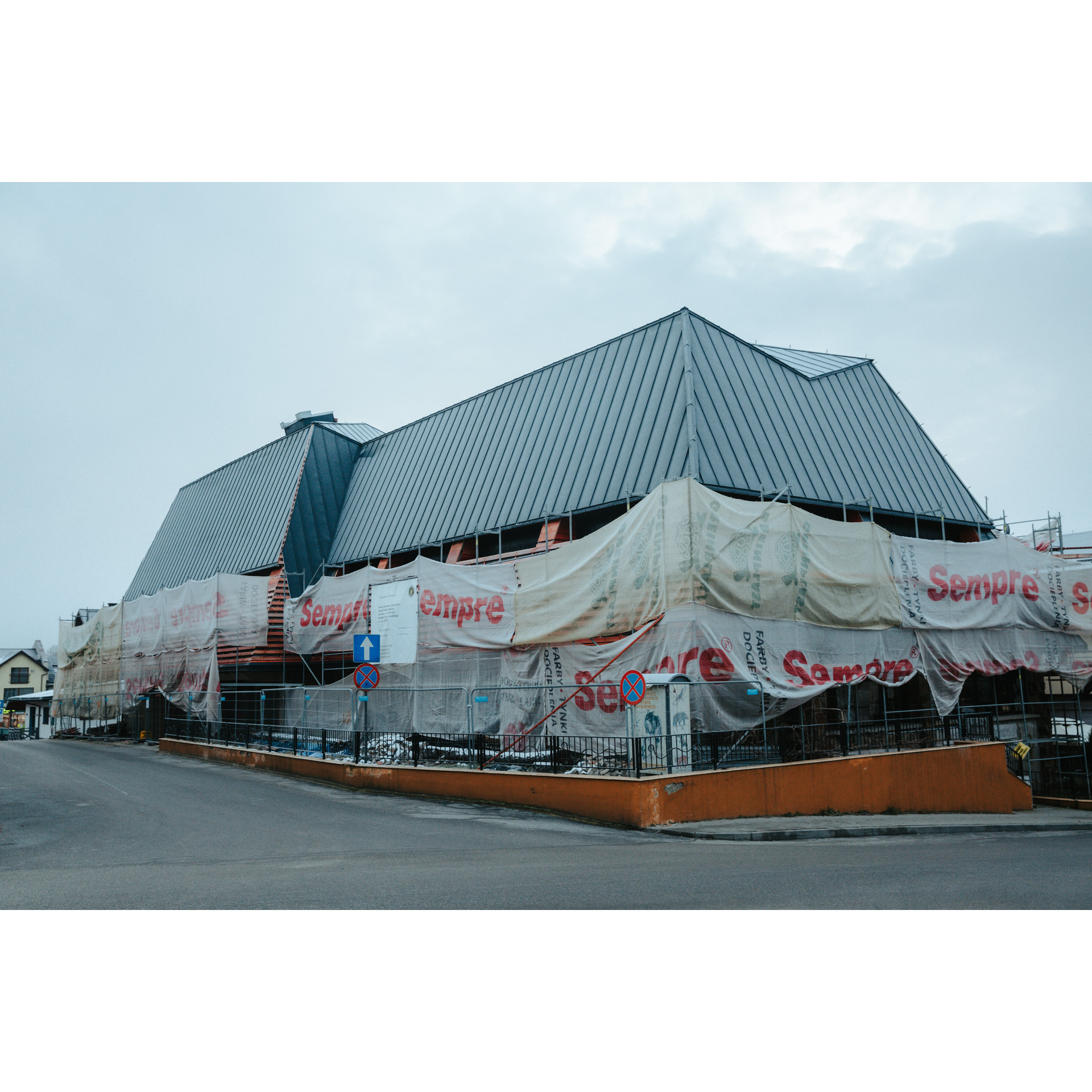 A building with a gray roof during renovation, covered with construction foil all around