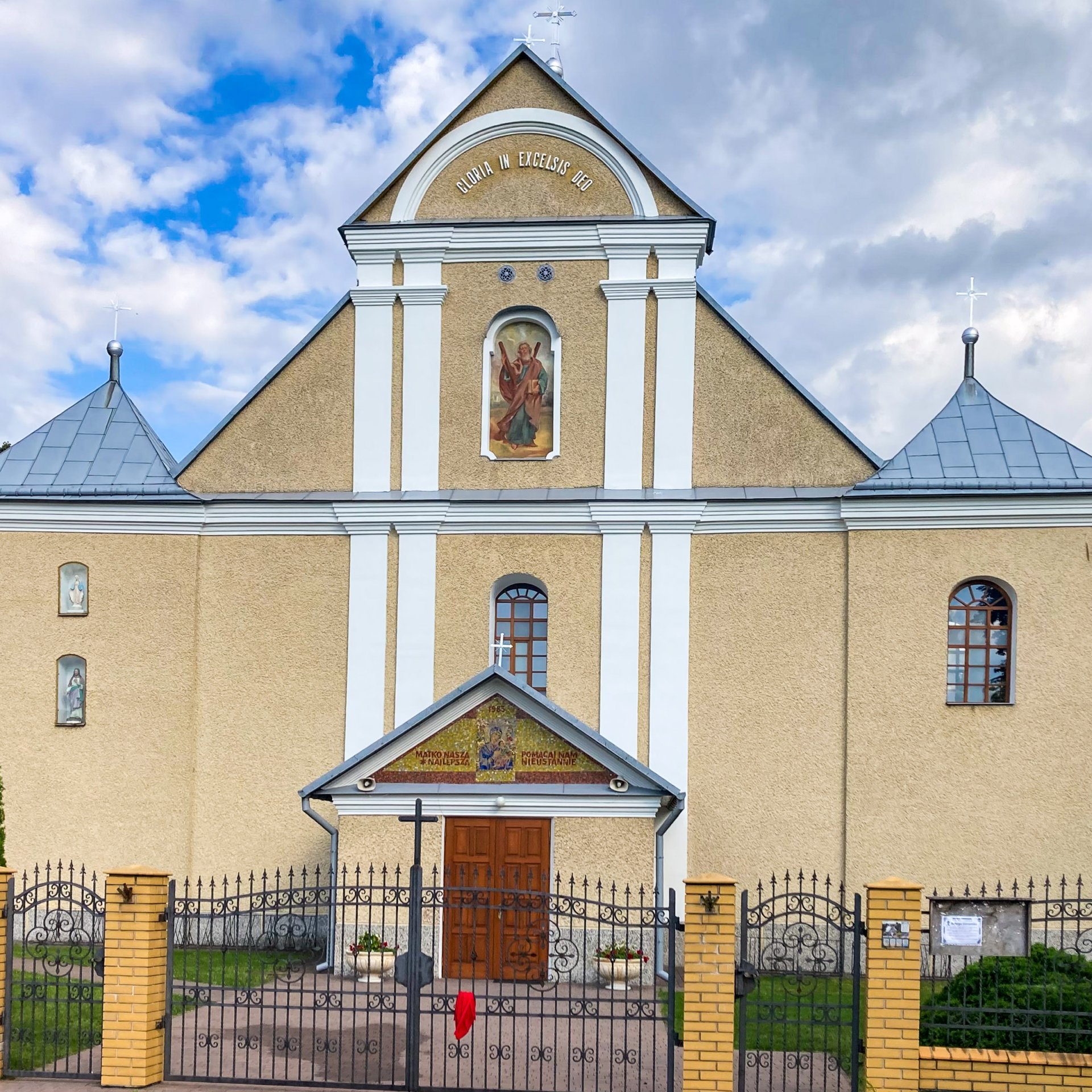 Fasada kościoła w kolorze żółtym z białymi kolumnami.