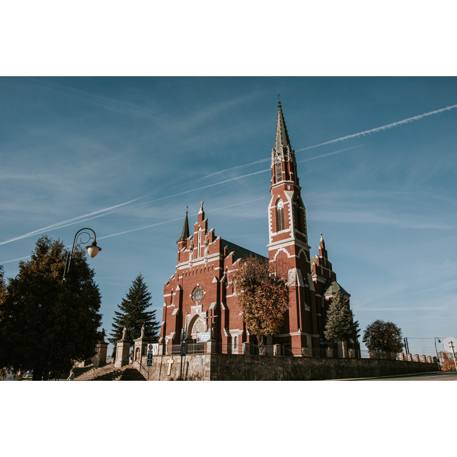 Strzelisty kościół z czerwonej cegły z białymi elementami
