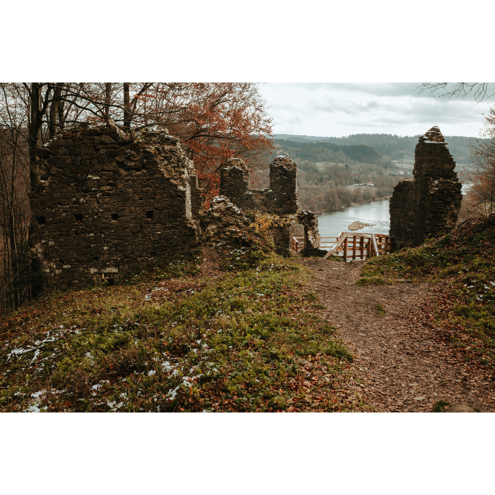Ruiny zamku z wejściem na drewniany taras widokowy na tle płynącej rzeki