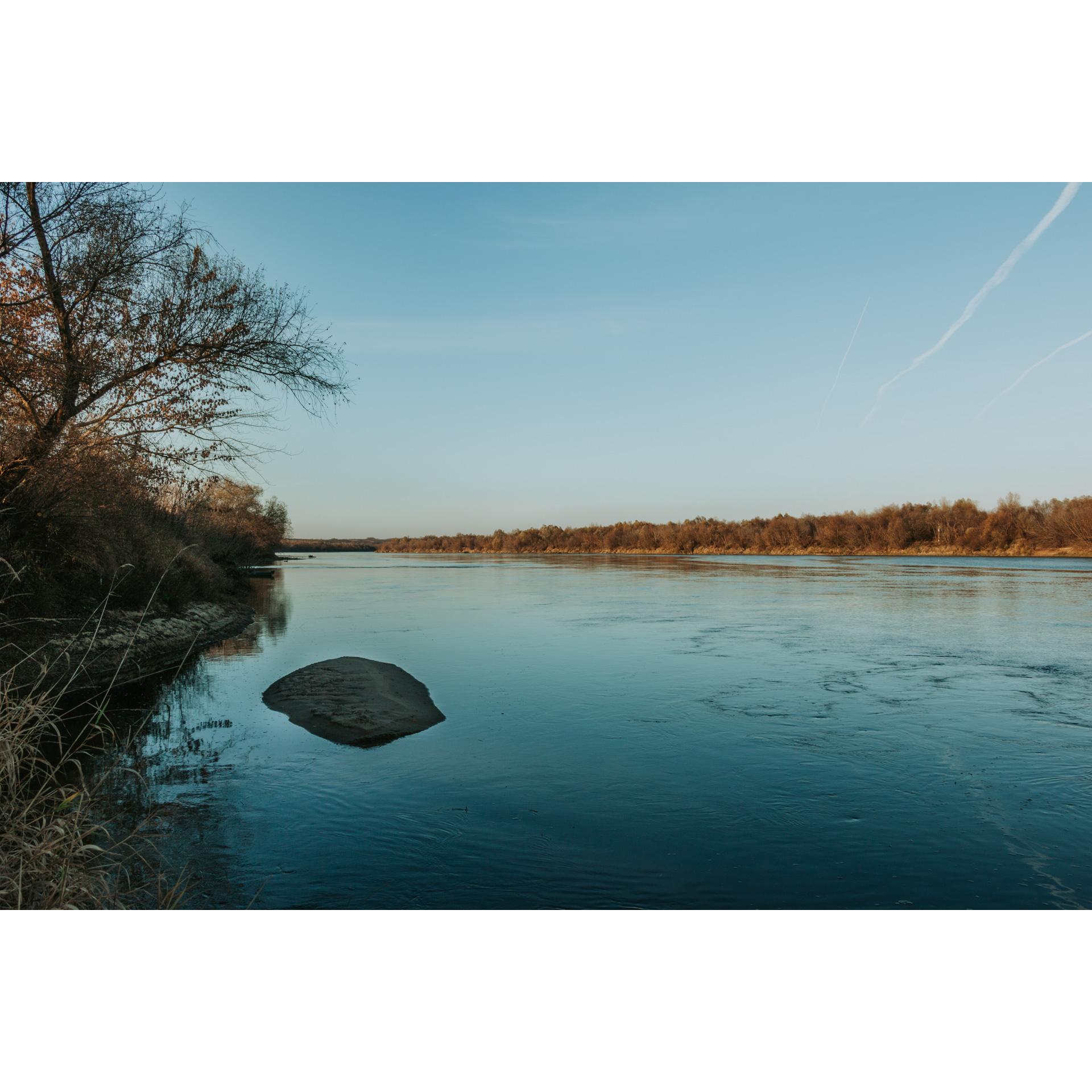 The shore of a wide body of water under a cloudless sky