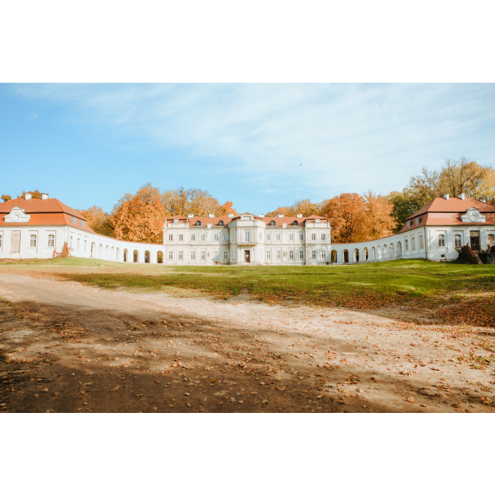 A bright, abandoned palace with many windows on two floors with a red roof