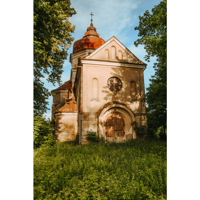 Jasna, murowana cerkiew z drewnianymi drzwiami i okrągłym oknem witrażowym