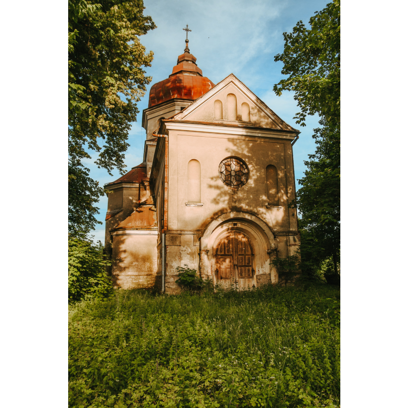 A bright, brick Orthodox church with a wooden door and a round stained-glass window