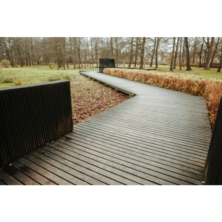 A wooden path in a park with trees visible in the background