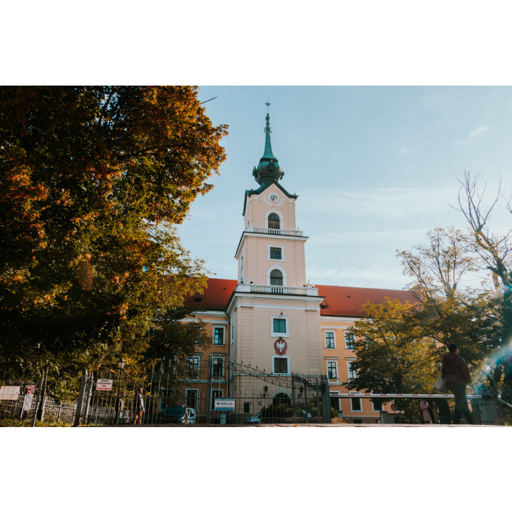 The tower of the castle with a clock and the emblem of Poland ended with a green turret among the trees