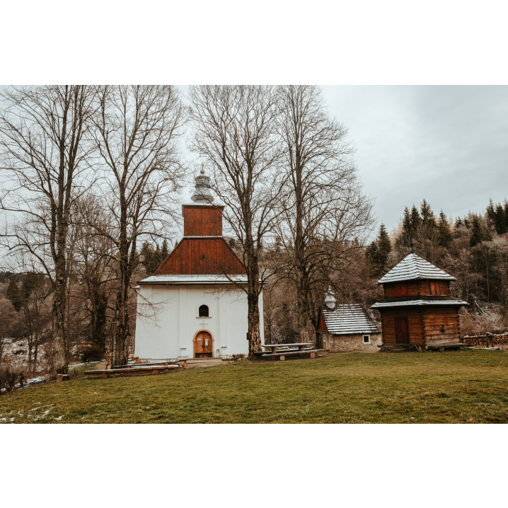 Entrance to the church with a wooden facade next to the old wooden belfry