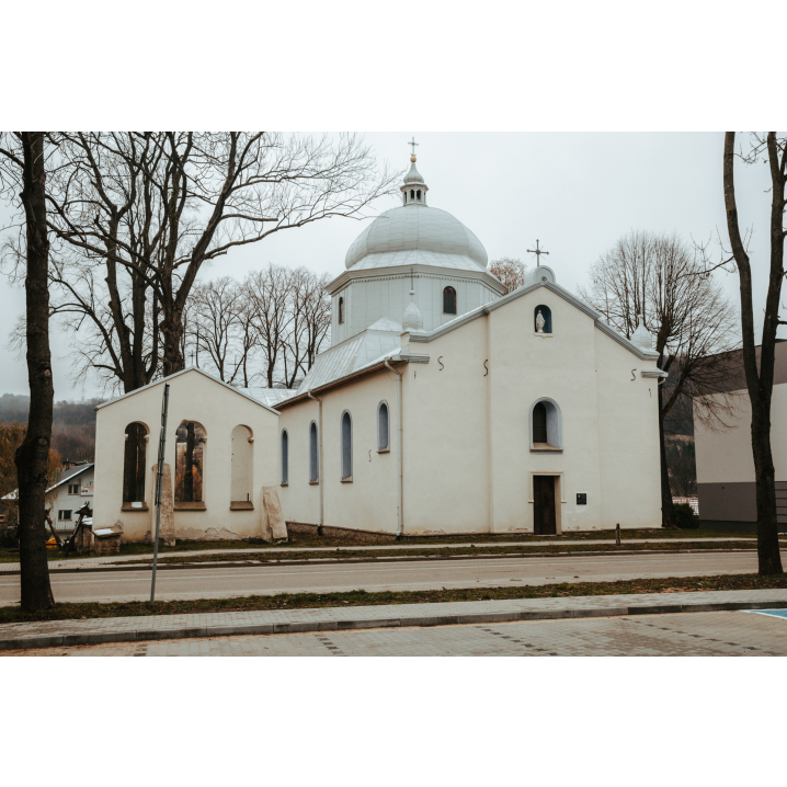 A view of the white, brick Orthodox church with a dome and a figure of Mary in the street's facade