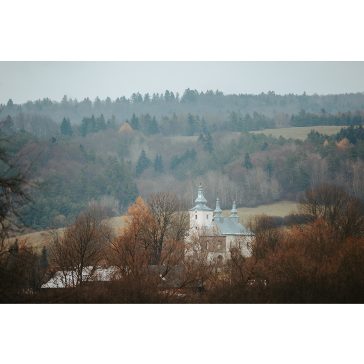 A view of a bright brick Orthodox church with three turrets among the rows of trees