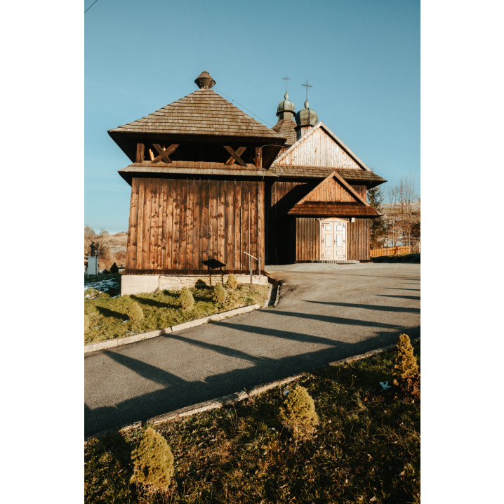 A wide road leading to a wooden church on a grassy hill