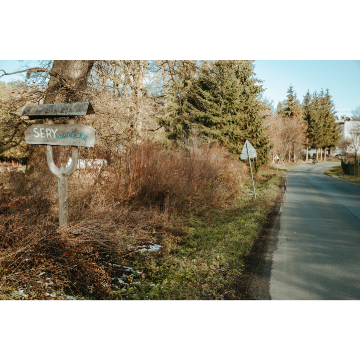 Wooden sign directing to the facility next to the asphalt road