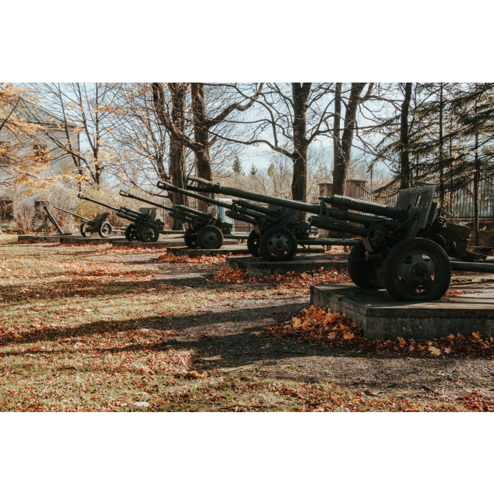 Pięć wyrzutni militarnych stojących na betonowych podestach wśród jesiennych drzew