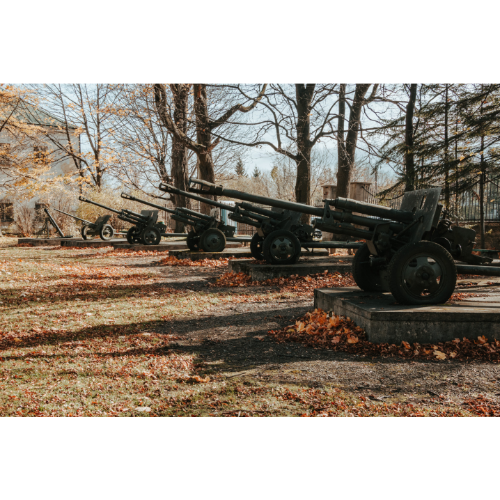 Five military launchers standing on concrete platforms among autumn trees