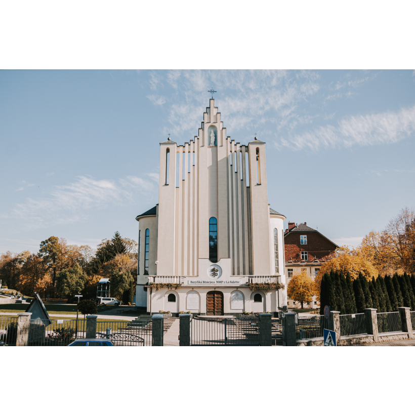 A tall, soaring church with a façade with three towers and concrete slats between them