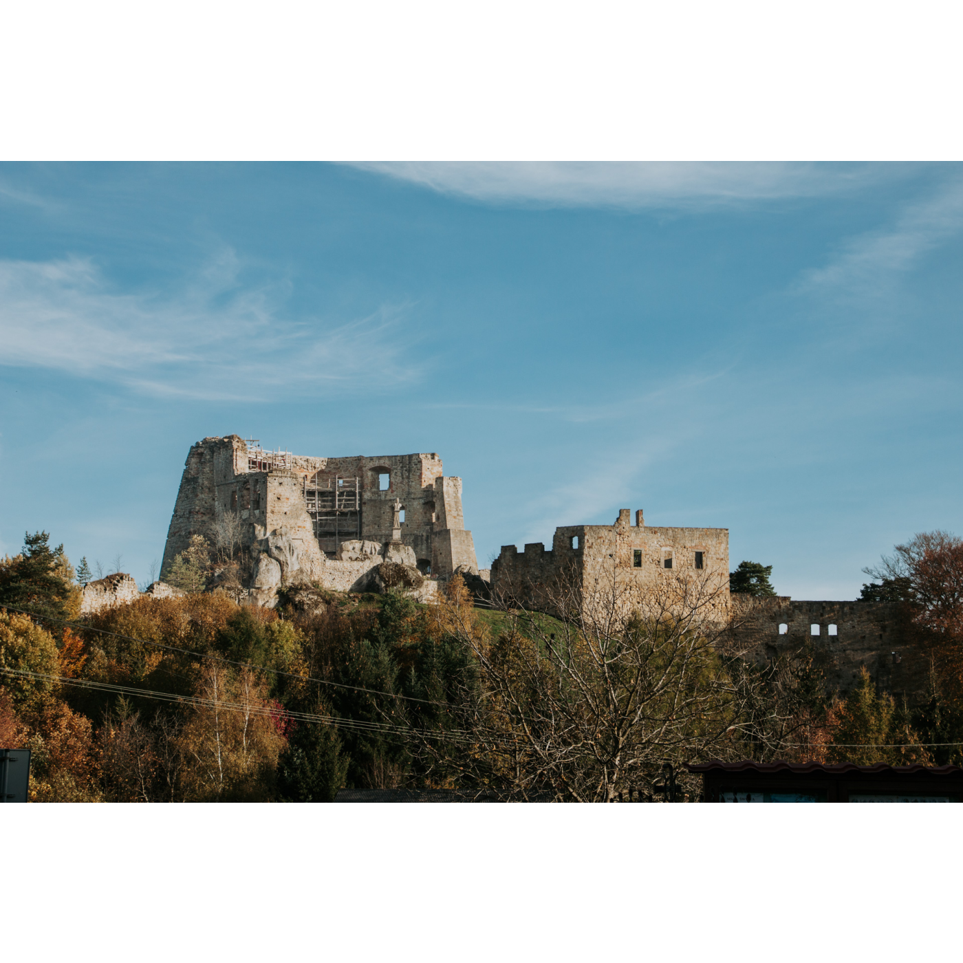 View of the castle ruins on a wooded hill against the blue sky