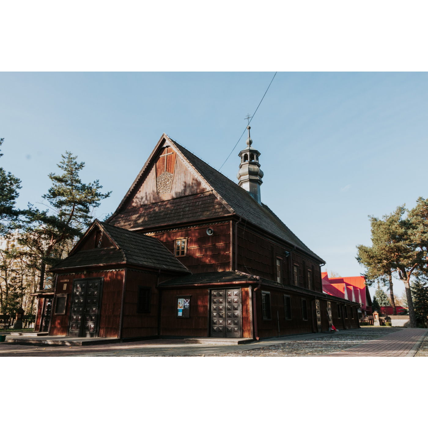 Mały drewniany kościół z ozdobnymi drzwiami i krzyżem w fasadzie
