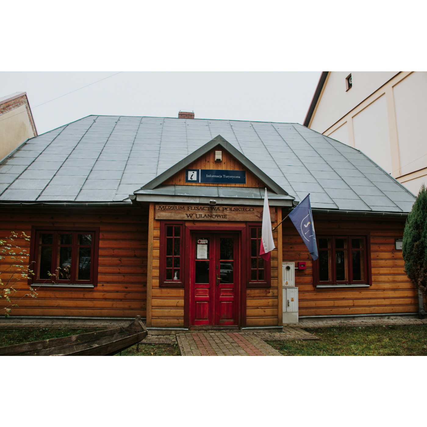 Entrance to a wooden museum building with red glass doors and a gray roof