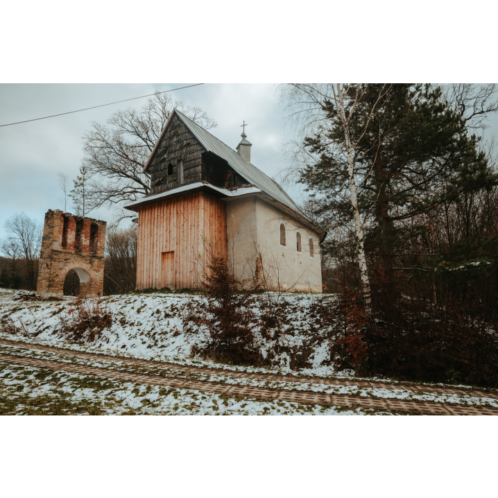 A small brick orthodox church with wooden elements on the front of the building, on the left side a fragment of a red brick belfry