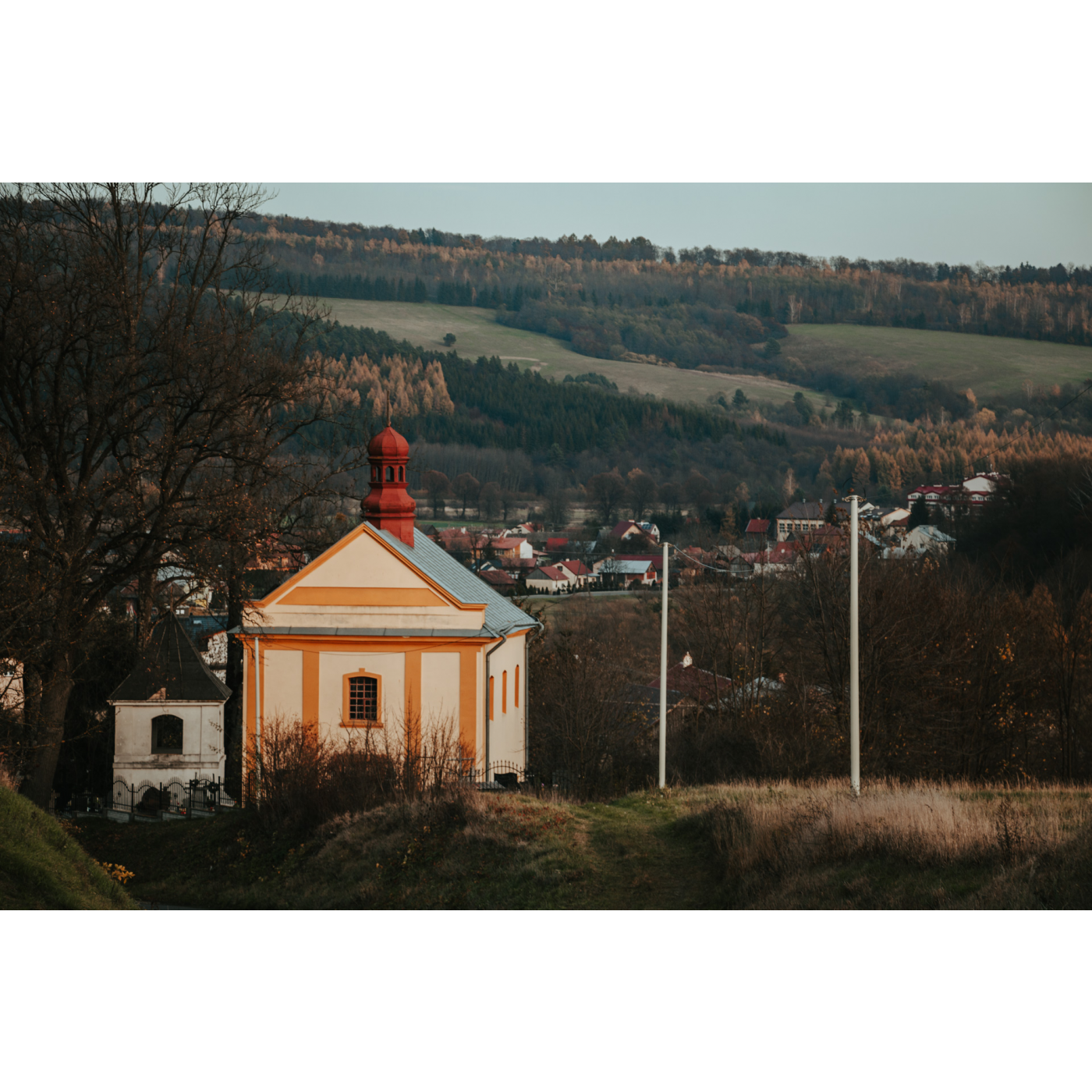 Pomarańczowo-beżowa cerkiew na tle jednorodzinnych zabudowań