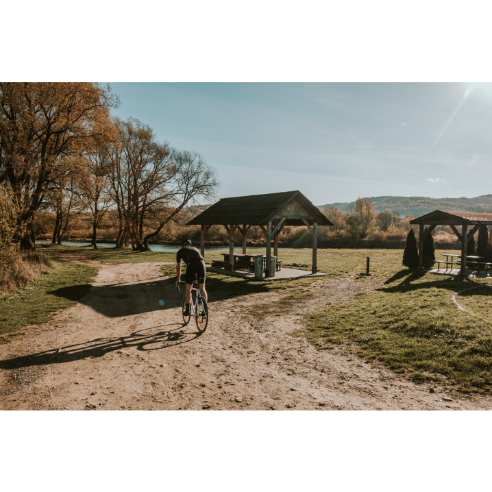 A cyclist in black clothes against the background of a wooden gazebo in a clearing